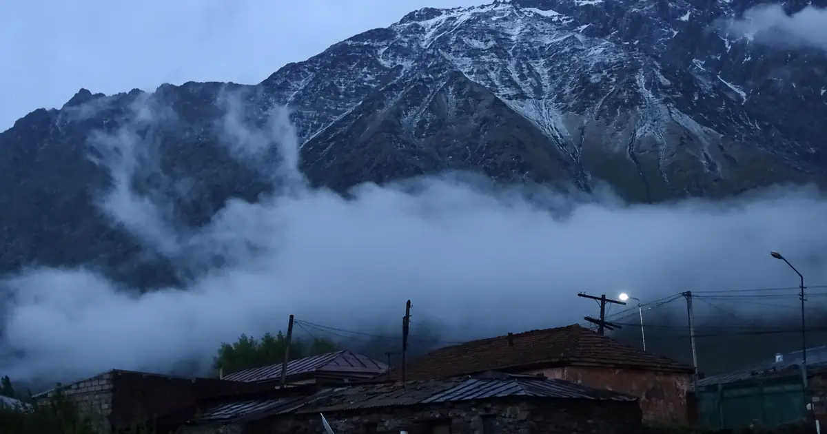Stepantsminda at dusk with clouds below Kazbek