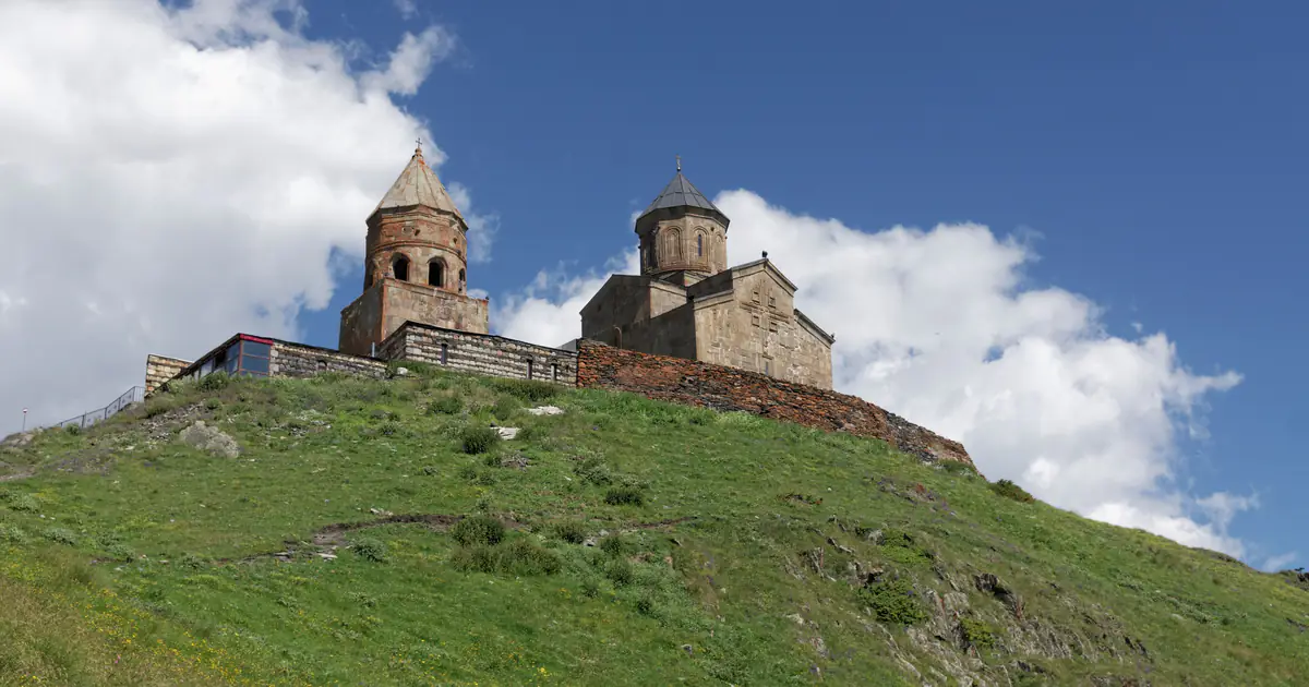Gergeti Trinity Church on a green slope below Kazbek