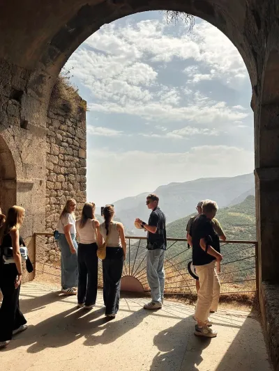 Tour group at monastery arch with mountain views