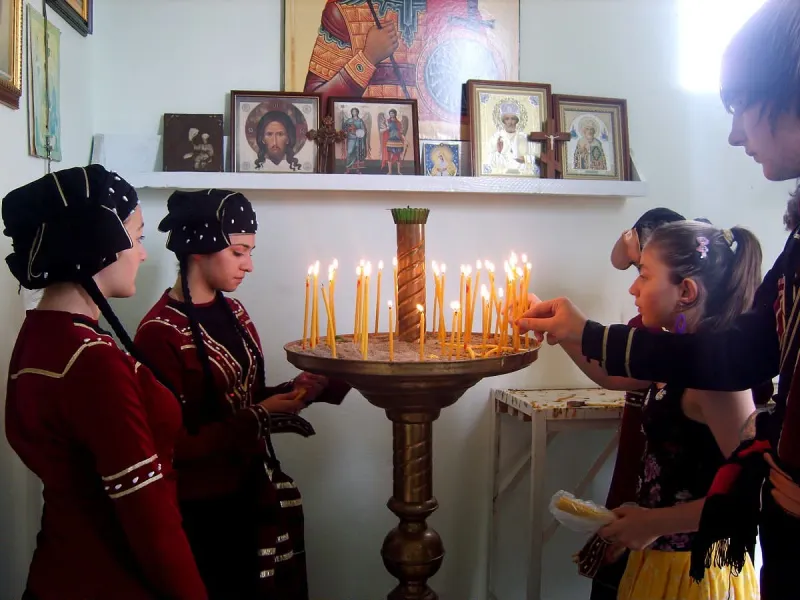 Дети в грузинских костюмах зажигают свечи в храме