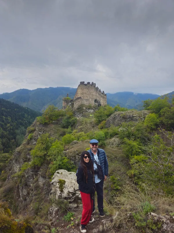Couple of travellers at medieval fortress ruins in the mountains of Georgia